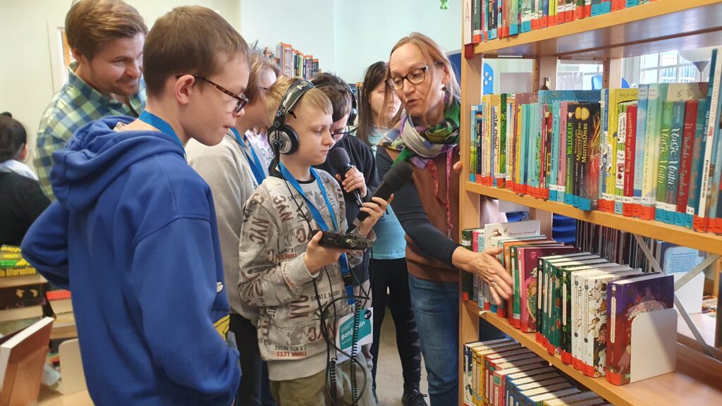 Bibliothekarin erklärt Schülern die Sortierung in einem Bücherregal