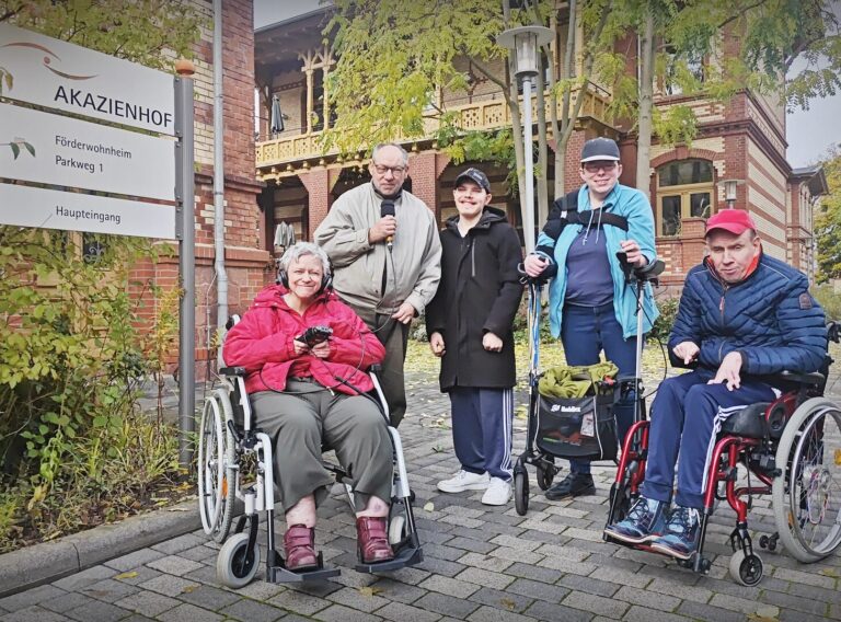 Gruppenbild der Redaktion Die Irrläufer vor einem Schild mit der Aufschrift Akazienhof